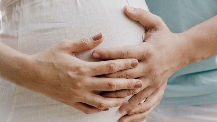 Femme enceinte se faisant toucher le
ventre par un homme avec sa main reposant sur la sienne